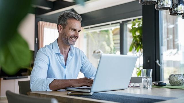 Working from home; man smiling with laptop